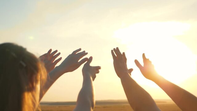 People's hands reach for the sun at sunset. Happy family together. Teamwork. A cry for help, People together in prayer turn to the sun.