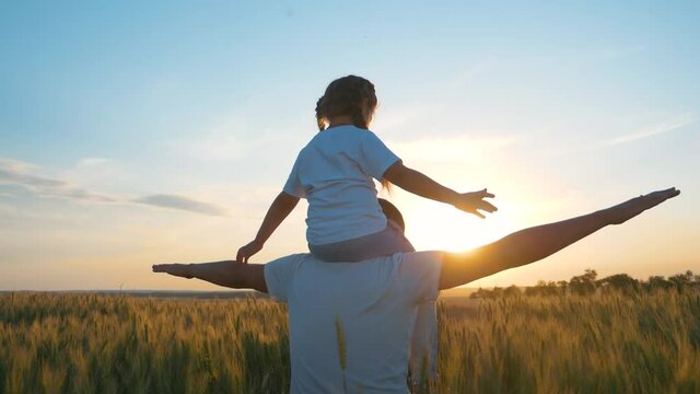 A happy boy on the shoulders of his father plays Aviator, the family spends time playing in the sunset sky. A dream of flight, travel, vacation. Happy family