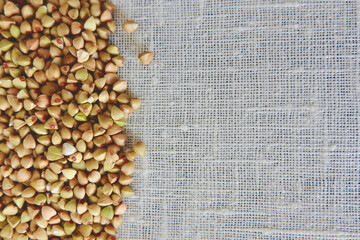 Green unprocessed buckwheat seeds on cotton material. Raw porridge, vegan diet
