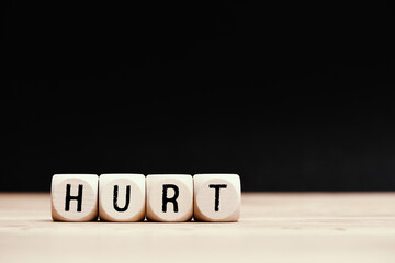 Social topic "Hurt" written on wooden cubes with dark background