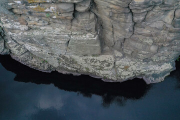 large stone rocks with a river between them with clear water. Trees grow on the rocks.	