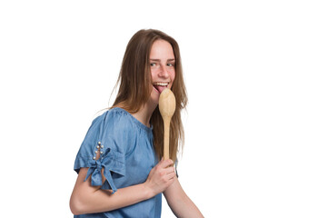 A young woman with long hair in a blue dress. he licks a large wooden spoon, Isolated on a white background