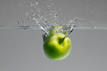 Green apple falls into water and creates beautiful air bubbles and water splashes