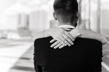 hands of the bride with a ring on the groom's shoulders
