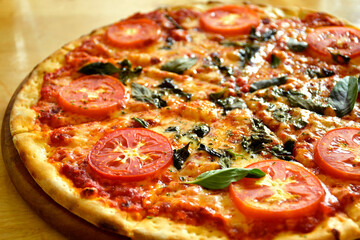 Close up Homemade pizza with cheese and tomatoes and basil on a wooden table with copy space.