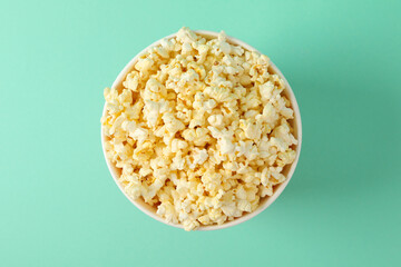 Cardboard bucket with tasty popcorn on mint background