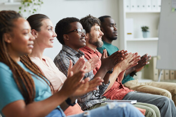 Side view portrait of multi-ethnic group of people applauding while sitting in row in audience or conference room, copy space - obrazy, fototapety, plakaty
