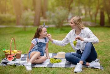 Mother Feeding Daughter Giving Her Grapes Having Family Picnic Outside