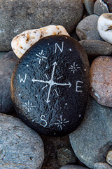 White compass painted on a black rock.