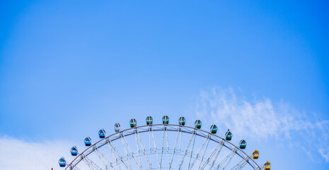 Partial view of a large ferris wheel with background of blue sky.