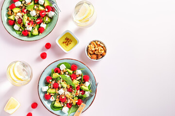 Light salad with raspberry, baby spinach, feta cheese, avocado and walnuts, top view. Fresh...
