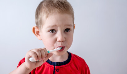 A little boy is learning to brush his teeth using a toothbrush. Concept of child hygiene and independence