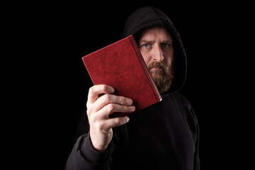 a bearded white man in a hood held a book in front of him