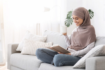 Obraz premium Weekend Pastime. Young Arab Woman Relaxing With Book And Coffee On Couch