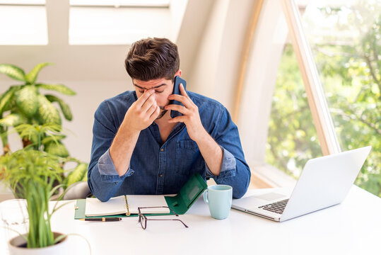 Stressed businessman having pain in his head while making a phone call