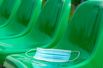 Medical mask on the green chairs of sports stadium