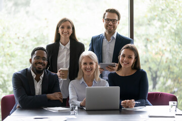 Happy multi national staff portrait. African and Caucasian young and old colleagues pose for camera smiling sit in office photo shooting for corporate album. Professional occupation, teamwork concept