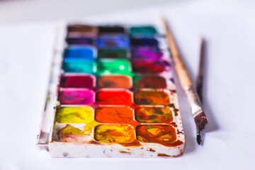watercolor palette of colors, the child draws and mixes colors with a brush