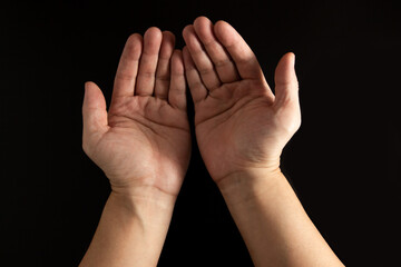 The man whose hand is praying for a blessing with a black or dark background.concept of religious prayer, ramadan.asking for help, poverty