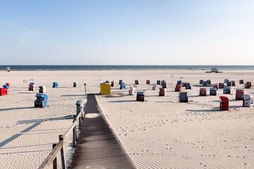 Path to the beach with colorful beach chairs in white sand on Frisian island of Juist.