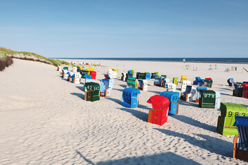Colorful beach chairs in white sand in the morning on the Frisian island of Juist.