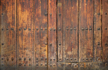 ancient and worn surface of wood from an old medieval door with rivets - rough texture background	