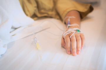 Close-up of Patient's hand on the bed in the hospital That is punctured with a needle and a tube for intravenous infusion saline solution