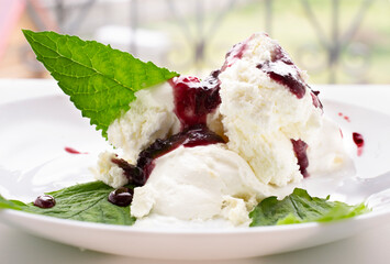 ice cream on a white plate with mint leaves poured with sorodin jam