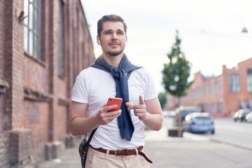 Handsome smiling man listening to music while walking in the city.