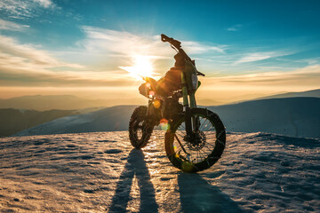 a motorcycle with chains on wheels stands on top of a mountain in winter