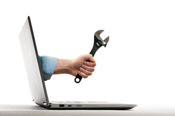 The human hand with  black wrench stick out of a laptop screen. Concept of technical support....