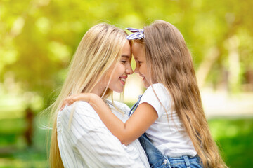 Fototapeta premium Cute Mother And Little Daughter Hugging Smiling Each Other Outside