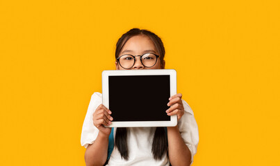Japanese Schoolgirl Showing Digital Tablet Blank Screen Over Yellow Background