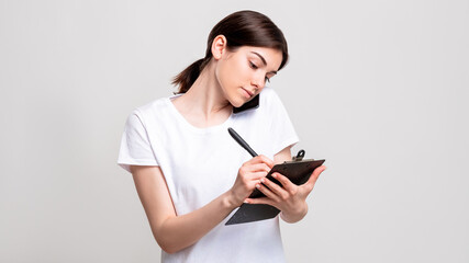 Fototapeta premium Business call. Reservation list. Confident woman with clipboard taking order on phone isolated on white copy space. Appointment arrangement. Client service.
