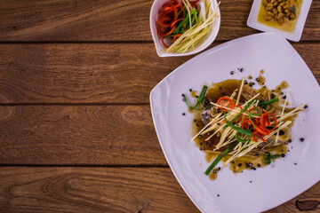 Steam fish with soy sauce is a clean food for good health. Presents in a flat lay, top view, copy space on wooden background.