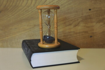 Close-up of an hourglass on a black book in the library