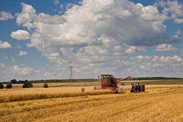 Kombajn zbożowy zbierający pszenicę i jadący ciągnik rolniczy
