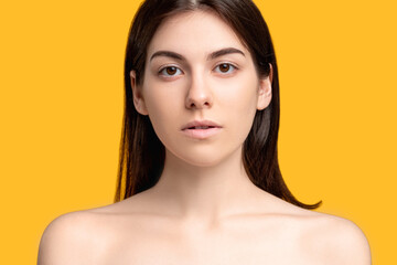 Aesthetic cosmetology. Plastic surgery. Portrait of woman with fresh pure perfect face skin bare shoulders isolated on orange copy space. Feminine beauty wellness.