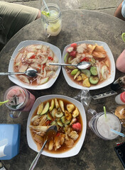 Image of assorted Balinese traditional fruit salad (Rujak Kuah Pindang) isolated on white plate and iced fruit as the complement drinking. Photographed from above.