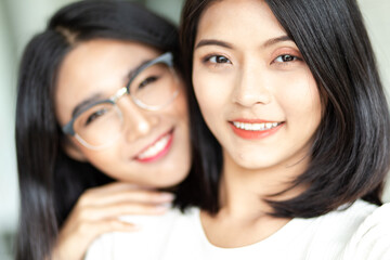 Close up smiling young asian lesbian couple hugging each other while sitting together on work at home time. LGBT Lesbian couple love moment.