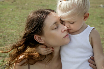 Outdoor candid portrait of mother with her toddler girl. Family time in nature, bonding and affection concept.