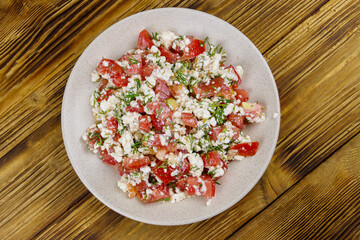 Tasty salad of tomato, cottage cheese, dill and olive oil on wooden table. Top view