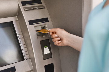 Close up of female hand inserting credit card in the ATM machine