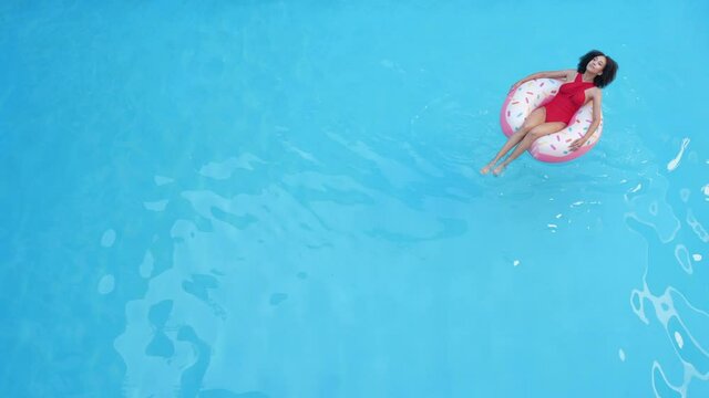 Only one lady floating in inflatable circle on blue water tanning relaxing spending time outdoors abroad on tropical resort, shooting from above full. Afro american woman swim pool in tube, long shot