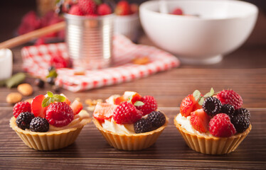 Delicious mini tart tartlets with fresh berries on wooden background