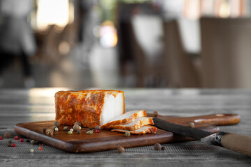 Whole piece of fresh smoked or salted lard, pepper, garlic on wooden cutting board