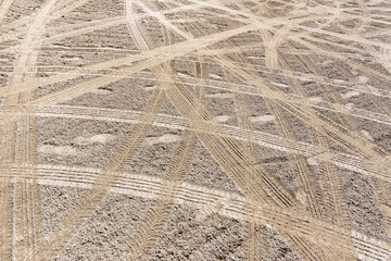Gravel surface with car tire tracks and foot prints