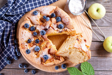 Tasty homemade apple pie with blueberries on a wooden board on the table. Top view