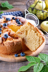 Apple cake with blueberries on a wooden board on the table. Charlotte with apples