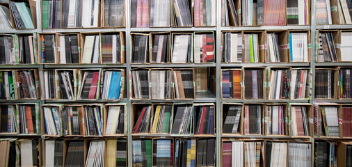 Neatly stacked records sit in rows on shelves at a warehouse ready for sale or distribution.